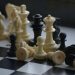 Close-up of scattered chess pieces on a black and white board.