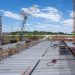 View of a busy construction site with cranes and building structure under clear sky.