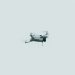 A single drone flying against a clear, pale sky in a minimalist composition.