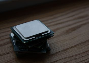 Close-up of multiple computer CPUs stacked on a wooden surface, showcasing technology components.
