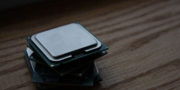 Close-up of multiple computer CPUs stacked on a wooden surface, showcasing technology components.