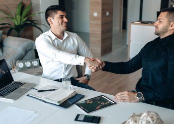 Two businessmen shaking hands in an office, symbolizing a successful business agreement.