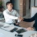 Two businessmen shaking hands in an office, symbolizing a successful business agreement.