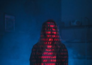 A mysterious silhouette with red binary code projected over the face, set against a dark, moody background.