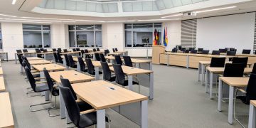 Spacious and modern meeting room in Niedersachsen, Germany, with desks and flags.