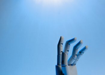 Robotic hand with articulated fingers reaching towards the sky on a blue background.
