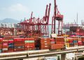 A bustling scene of cargo containers and cranes at a Hong Kong port, showcasing global trade.