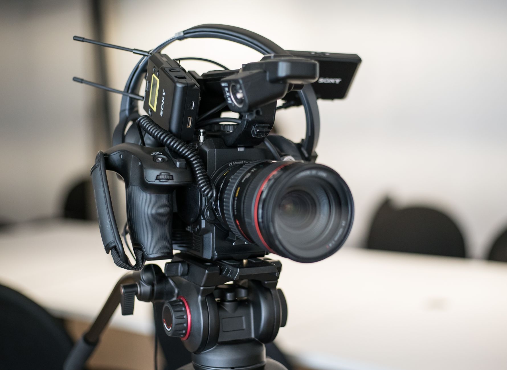 Close-up of a professional video camera setup on a tripod for videography use in a studio setting.