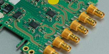 Detailed view of a green circuit board featuring multiple connectors and intricate components.