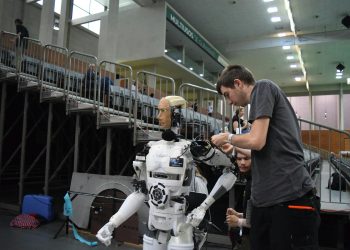 Technician working on humanoid robot at a tech exhibition in Guimaraes, Portugal.