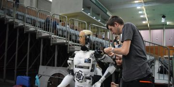 Technician working on humanoid robot at a tech exhibition in Guimaraes, Portugal.