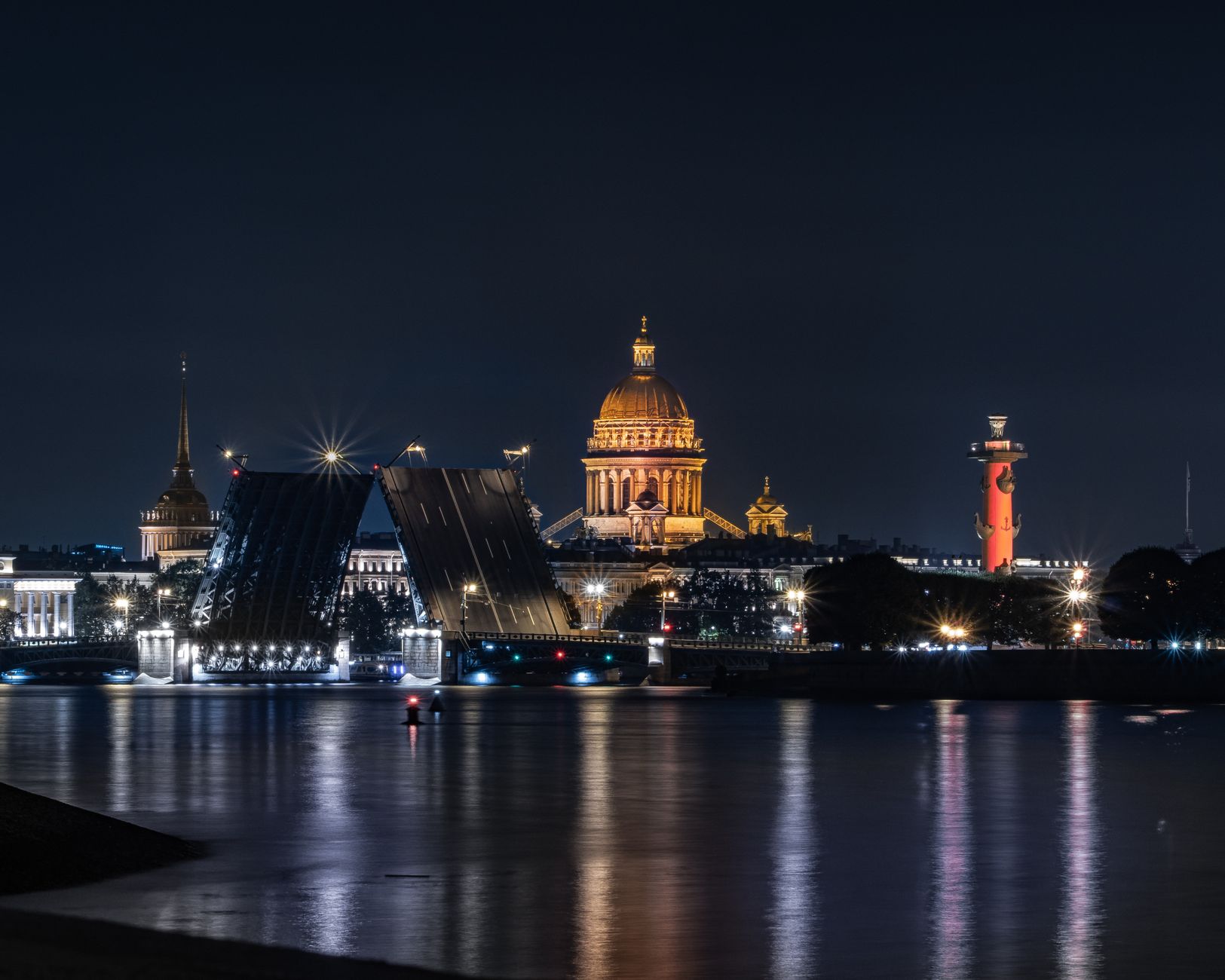 Night view of Saint Petersburg with iconic bridge and cathedral illuminated.