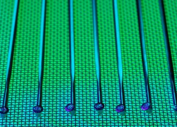 Vivid and detailed close-up of a patterned silicon wafer with vibrant green and blue colors.