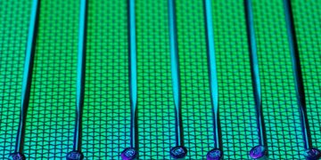 Vivid and detailed close-up of a patterned silicon wafer with vibrant green and blue colors.