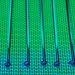 Vivid and detailed close-up of a patterned silicon wafer with vibrant green and blue colors.