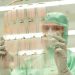 Scientist in protective gear holding a transparent test sheet in a laboratory.