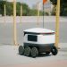 Futuristic autonomous delivery robot navigating a city street, showcasing modern technology.