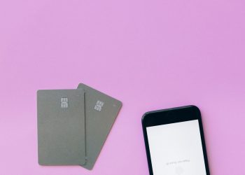 Flat lay of credit cards and smartphone on pink surface, symbolizing digital payment solutions.