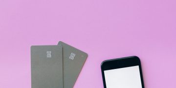 Flat lay of credit cards and smartphone on pink surface, symbolizing digital payment solutions.