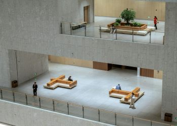 Spacious modern atrium in a Shanghai building featuring minimalistic design with people sitting and walking.