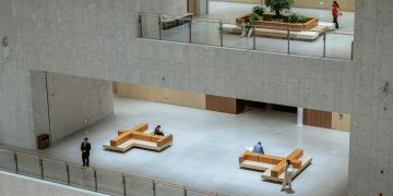 Spacious modern atrium in a Shanghai building featuring minimalistic design with people sitting and walking.