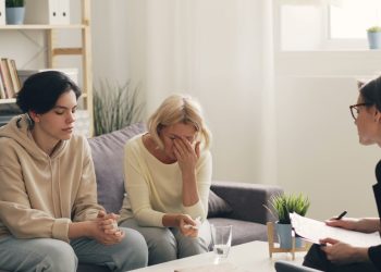 two women sitting on a couch talking to each other