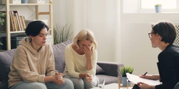 two women sitting on a couch talking to each other