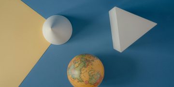 Abstract arrangement of geometric shapes and a globe on a colorful background.