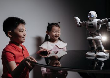Two children interacting with a robot toy on a table, showcasing modern technology.