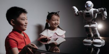 Two children interacting with a robot toy on a table, showcasing modern technology.