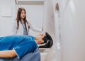 A doctor stands beside a patient in an MRI room, ensuring a smooth examination process.