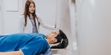 A doctor stands beside a patient in an MRI room, ensuring a smooth examination process.