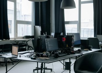 Contemporary workspace featuring computers, coding screens, and office essentials in a tech environment.