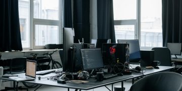 Contemporary workspace featuring computers, coding screens, and office essentials in a tech environment.
