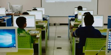 Children focus on computers in a modern classroom setting.