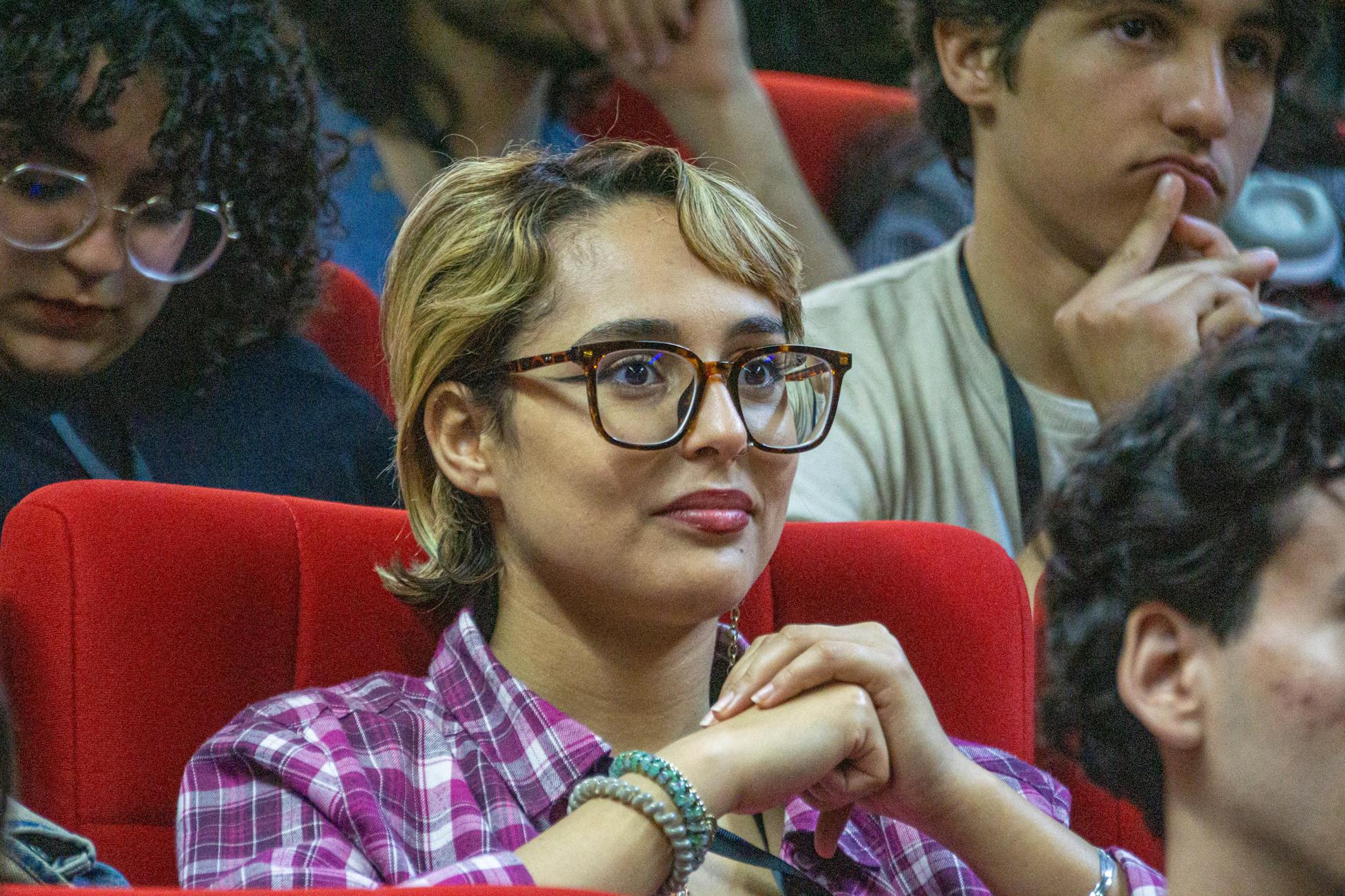 Young adults attentively listening during a conference session, seated in a lecture hall.