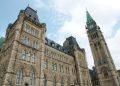 A view of the historical Parliament Hill building in Ottawa against a clear sky.