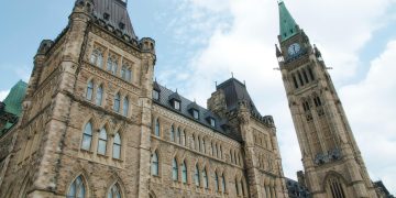 A view of the historical Parliament Hill building in Ottawa against a clear sky.