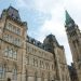 A view of the historical Parliament Hill building in Ottawa against a clear sky.