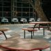 Futuristic delivery robots lined up near outdoor cafeteria tables, showcasing modern technology.