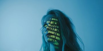 A woman with binary code lights projected on her face, symbolizing technology.
