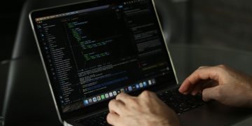 Close-up of hands coding on a laptop, focusing on programming productivity.