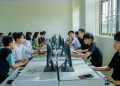 Diverse group of students studying in a computer-equipped classroom setting.