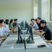 Diverse group of students studying in a computer-equipped classroom setting.