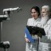 Researchers examining a robotic arm, showcasing technology and innovation.