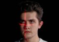 Conceptual portrait with laser scanning for facial recognition on plain black background.