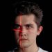Conceptual portrait with laser scanning for facial recognition on plain black background.