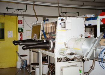 An industrial laboratory setup featuring a glove box with safety equipment.