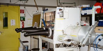 An industrial laboratory setup featuring a glove box with safety equipment.