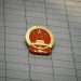 Close-up of the Chinese national emblem on a large concrete building facade, symbolizing government presence.